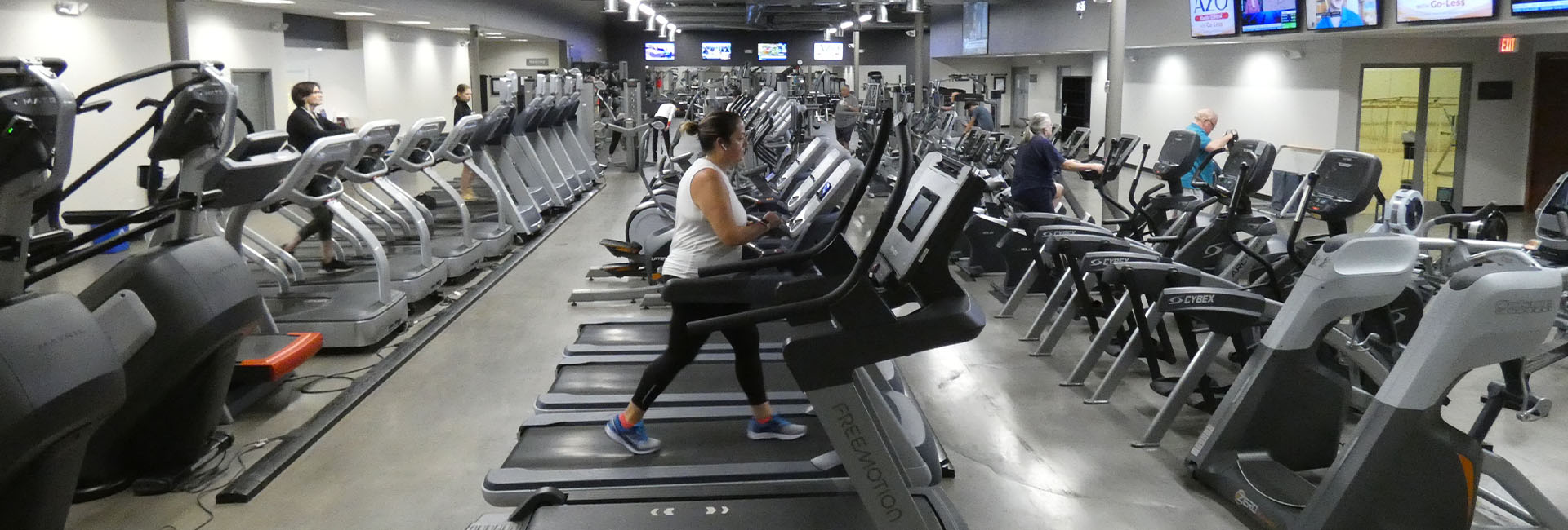 woman using a treadmill in a large cardio floor